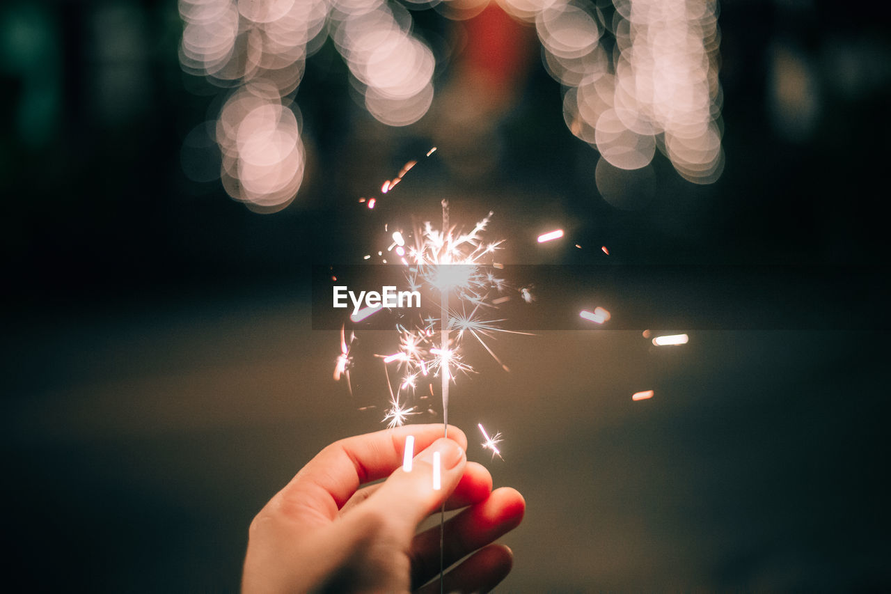 Close-up of person holding sparkler at night