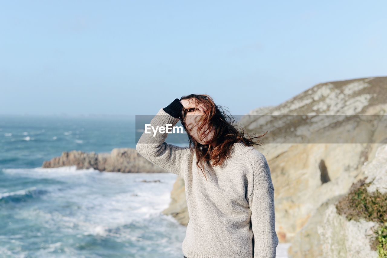 Woman standing at beach against clear sky