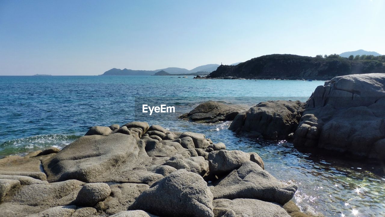 ROCKS ON SHORE AGAINST CLEAR SKY