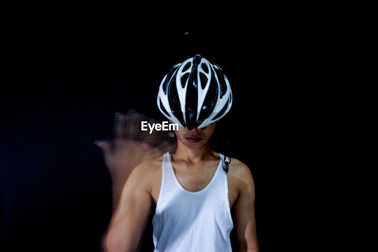 Man wearing sports helmet against black background