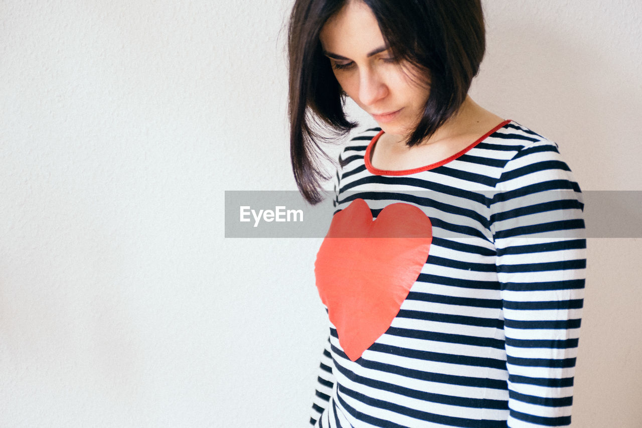 Woman with heart shape on t-shirt against white background