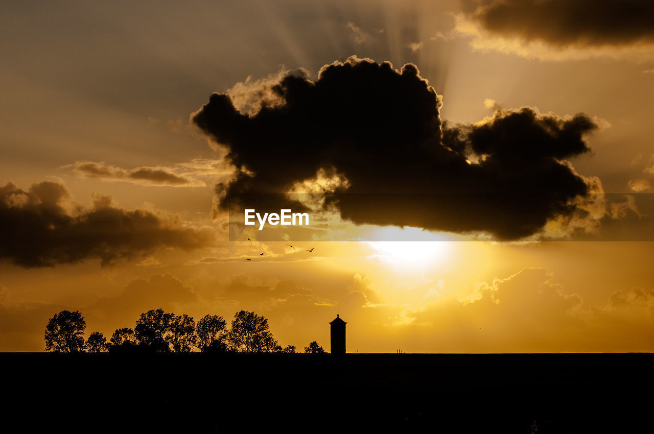 Silhouette of building against cloudy sky during sunset