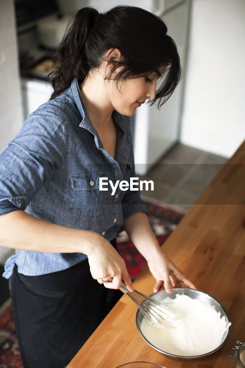 High angle view of woman making whipped cream