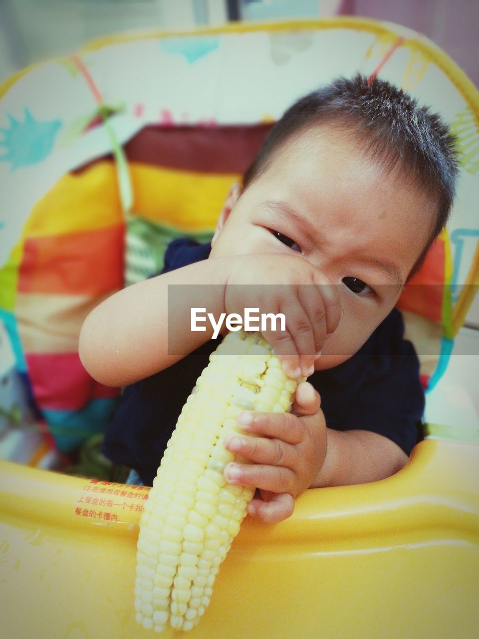 Close-up of baby with corn in stroller