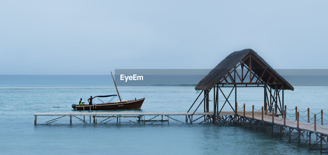 Boat by pier in sea against clear sky