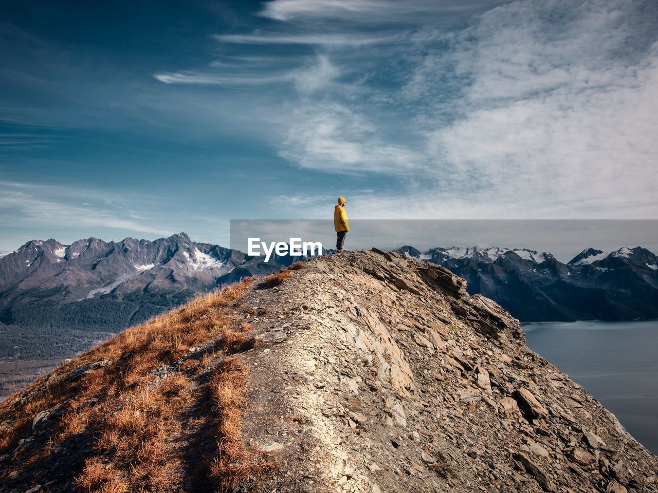 Man standing on rock formation against sky