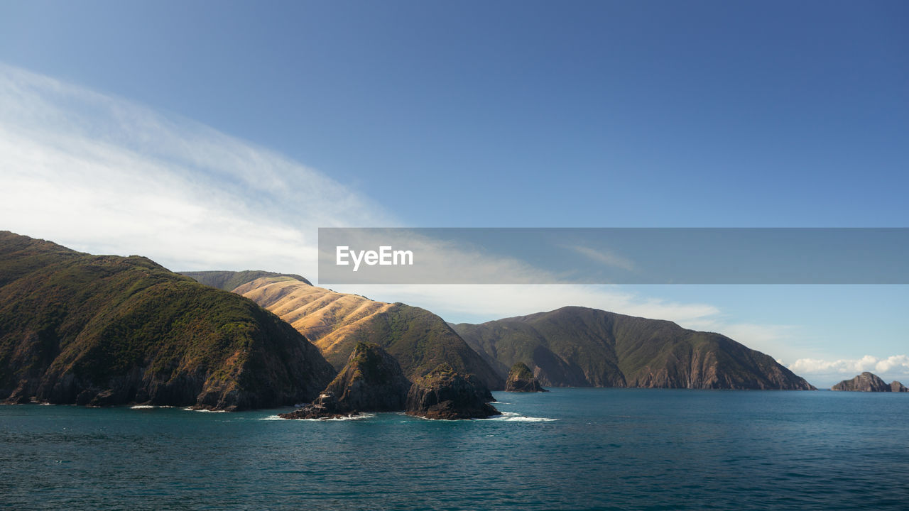PANORAMIC SHOT OF SEA BY MOUNTAINS AGAINST SKY