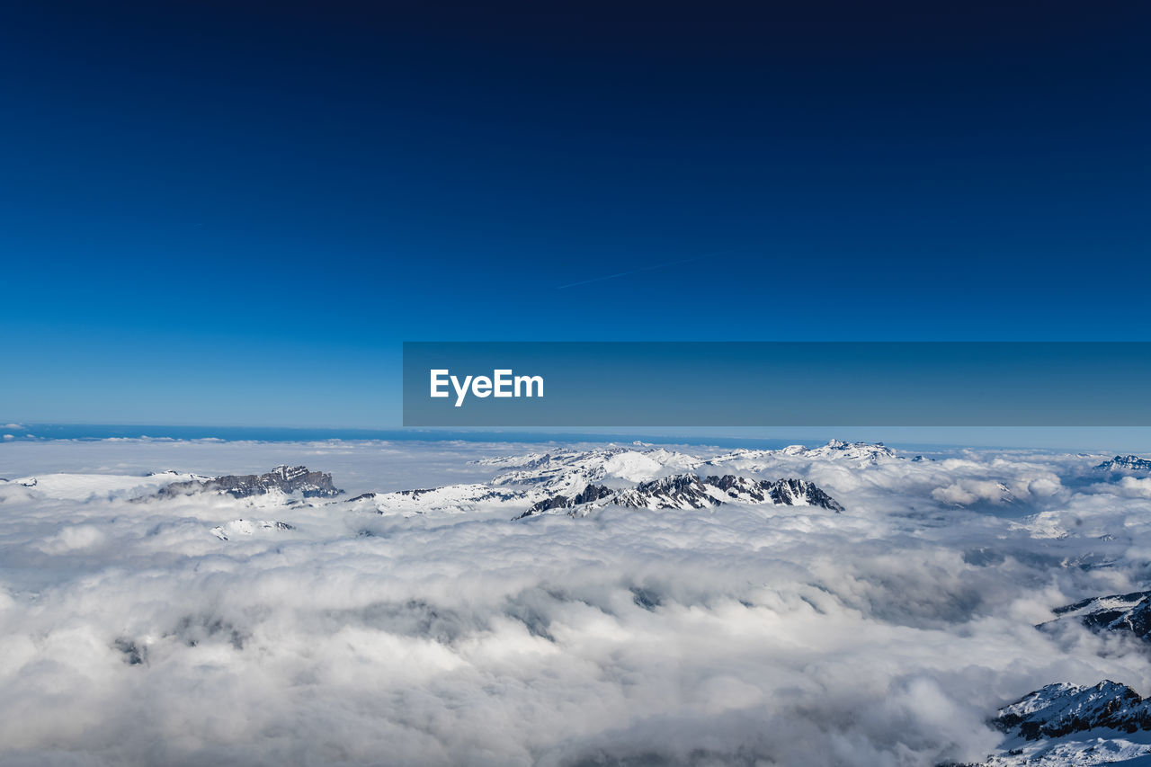 Scenic view of snowcapped mountains against blue sky