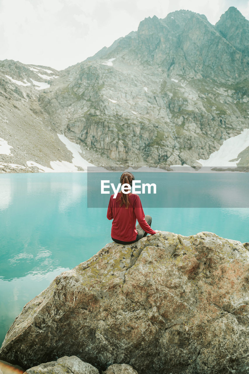 YOUNG WOMAN ON ROCK BY LAKE