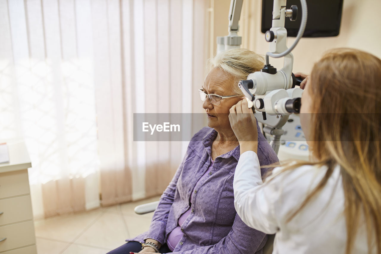 Ent physician examining ear of a senior woman