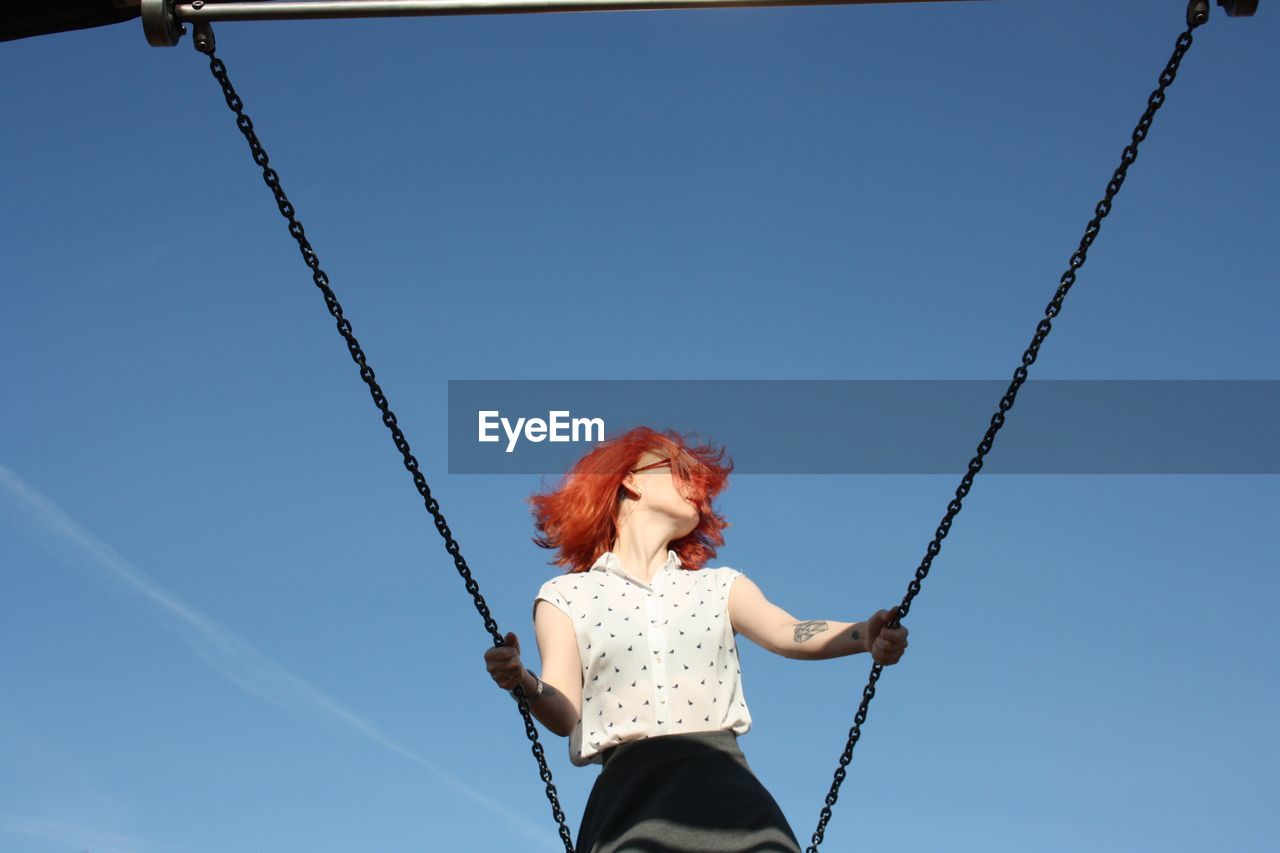 Young woman on swing against sky