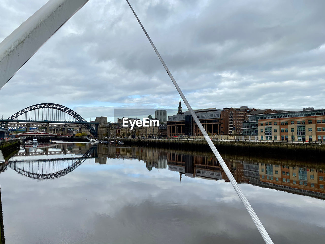 Bridge over river in city against sky