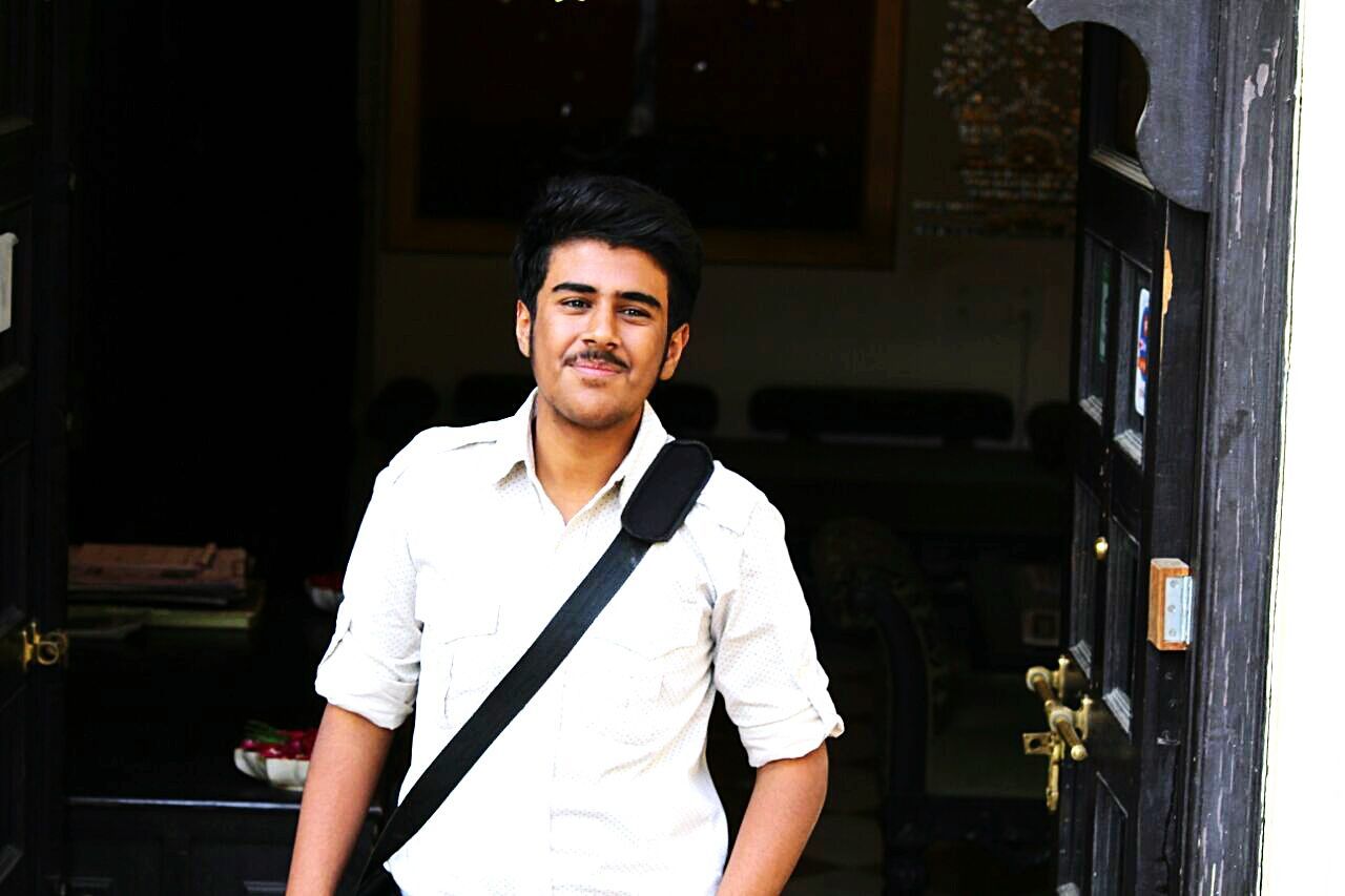 Portrait of smiling young man standing at doorway