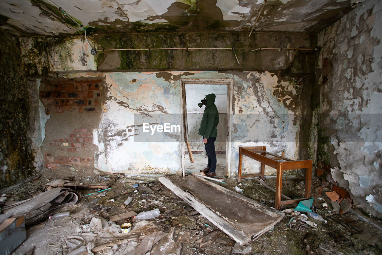 MAN STANDING ON OLD ABANDONED BUILDING