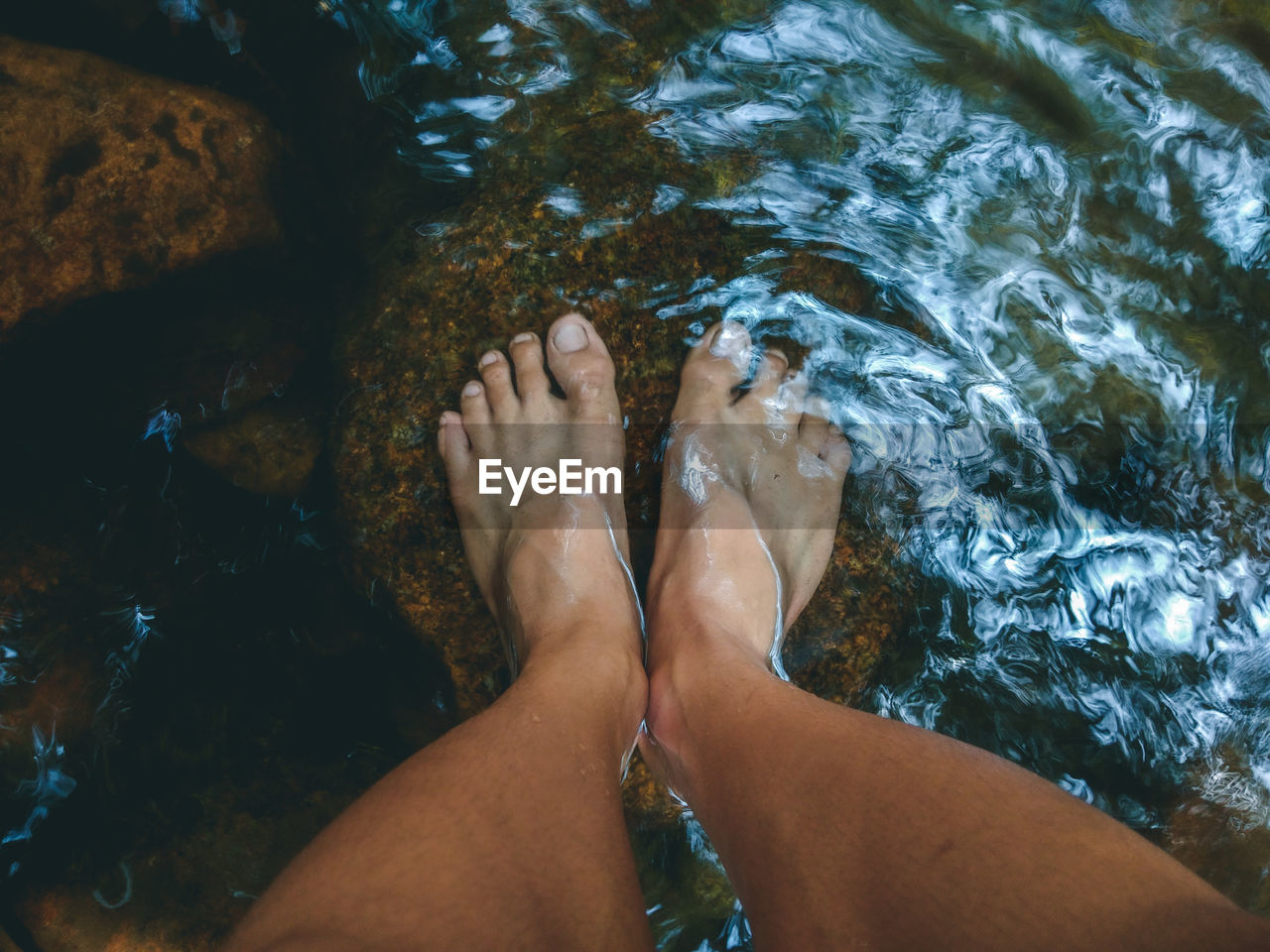 Low section of person on rock in sea