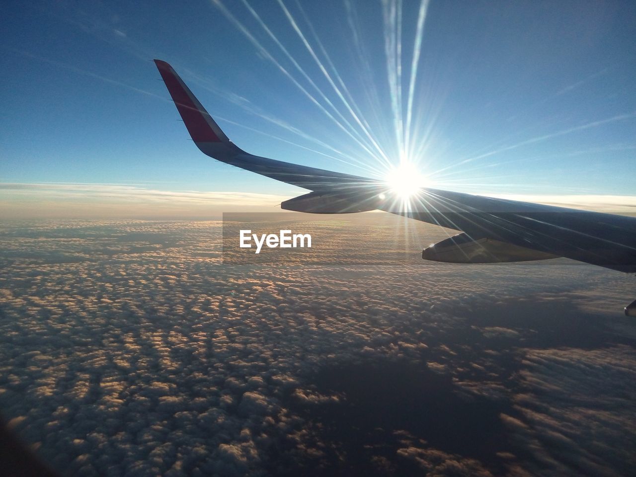 AIRPLANE FLYING OVER LANDSCAPE AGAINST SKY