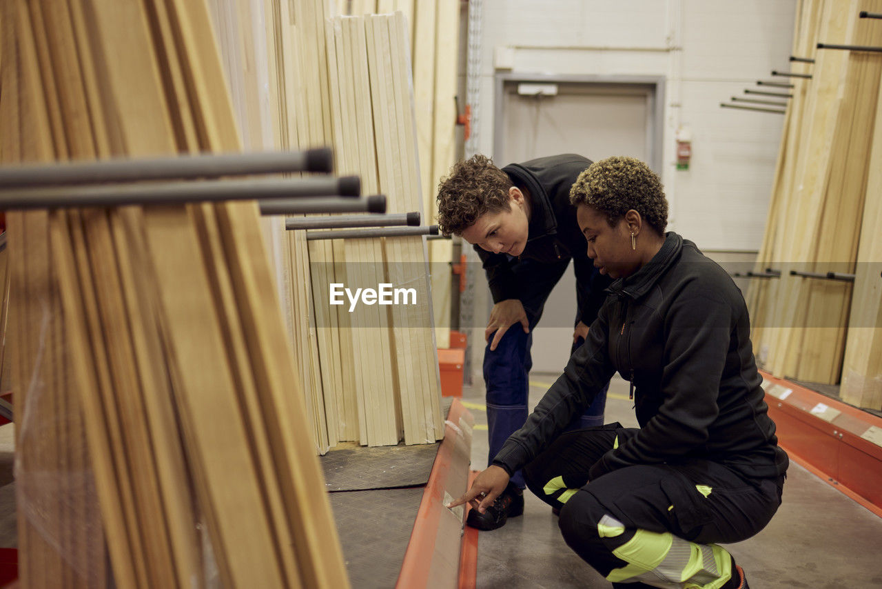 Multiracial female colleagues discussing over label in distribution warehouse of lumber industry