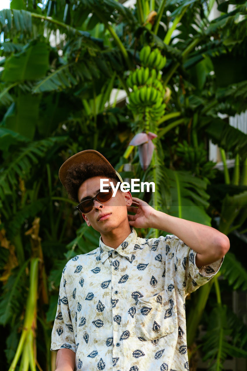 A young guy wearing summer clothing. palm tree as background.