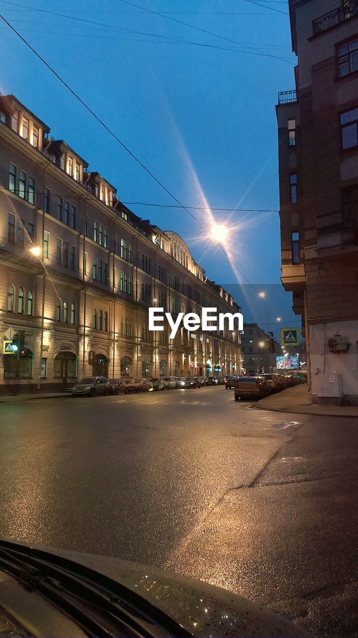 ILLUMINATED CITY STREET AGAINST SKY AT NIGHT