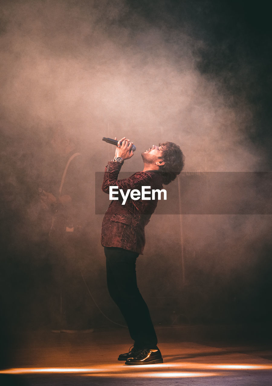 Side view of young man singing