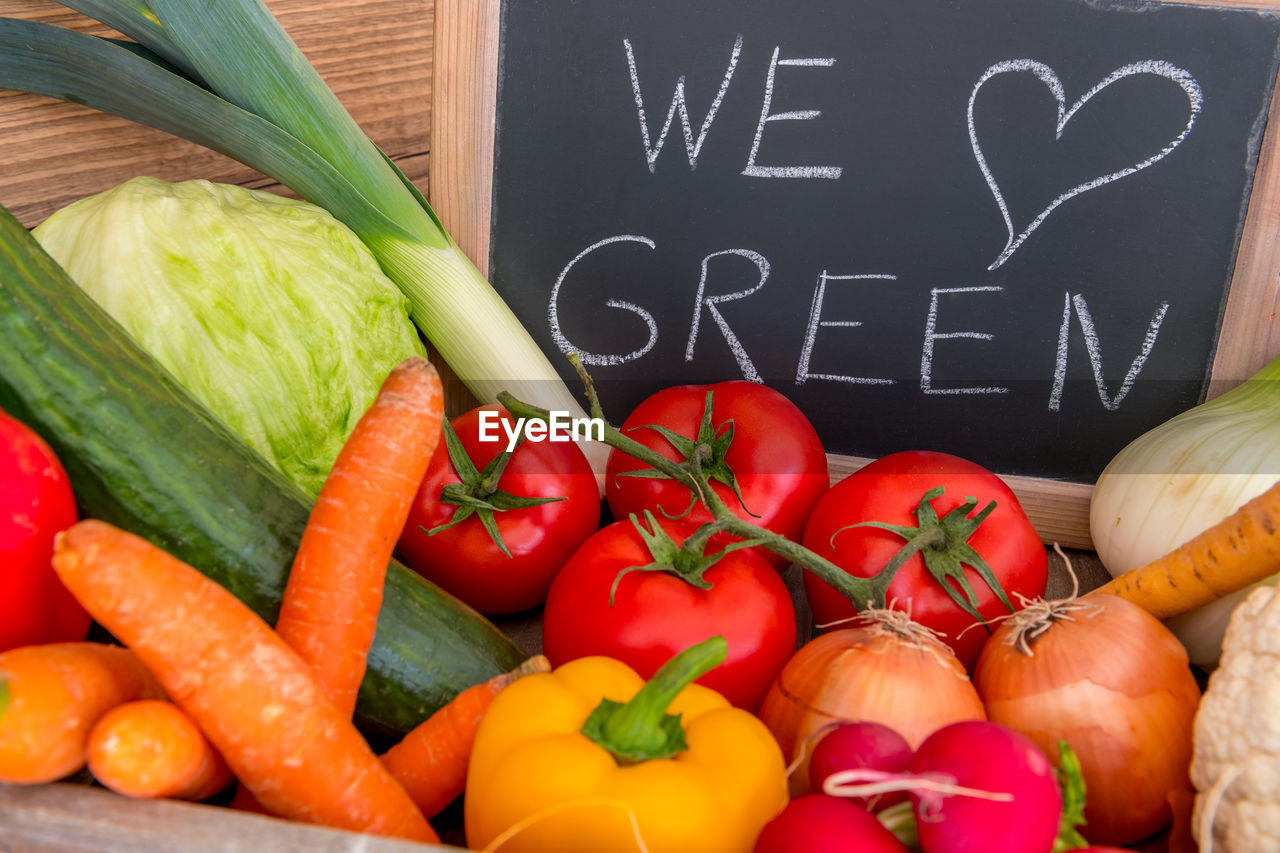 Various vegetables in a box. we love green, standing on a blackboard in the background.