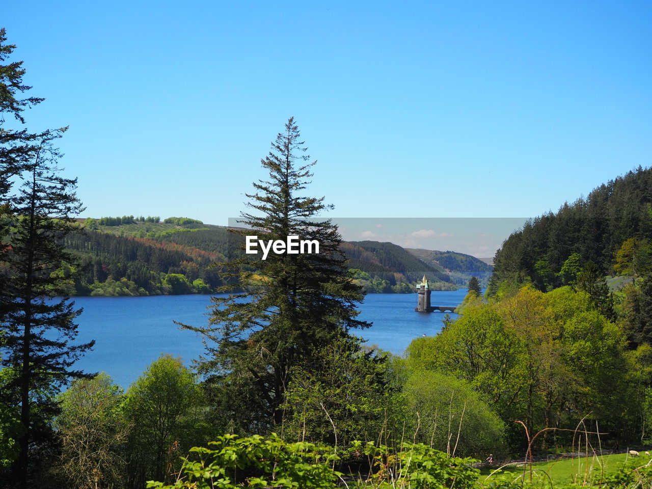 Water tower of lake vyrnwy surrounded by forestry and clear blue skies 