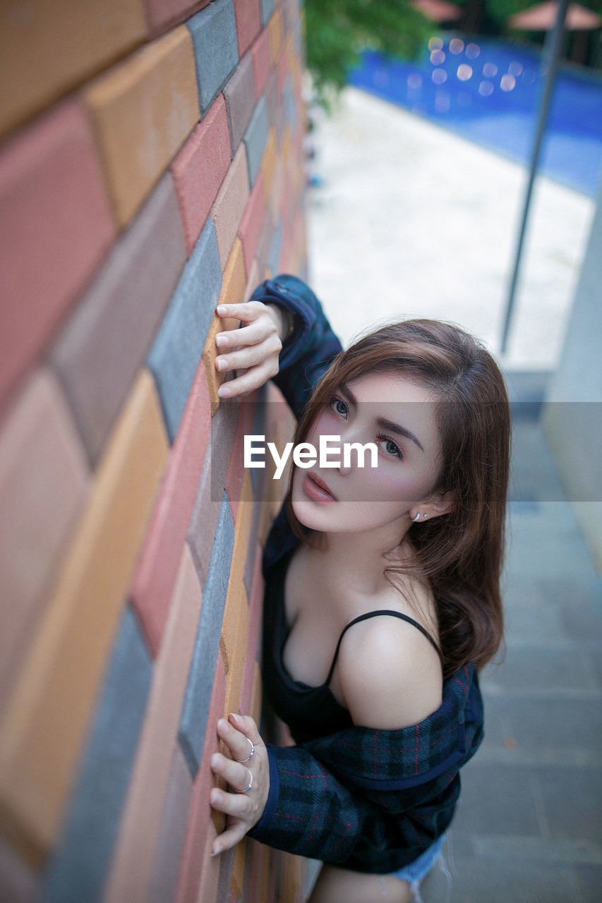 Portrait of young woman standing against wall