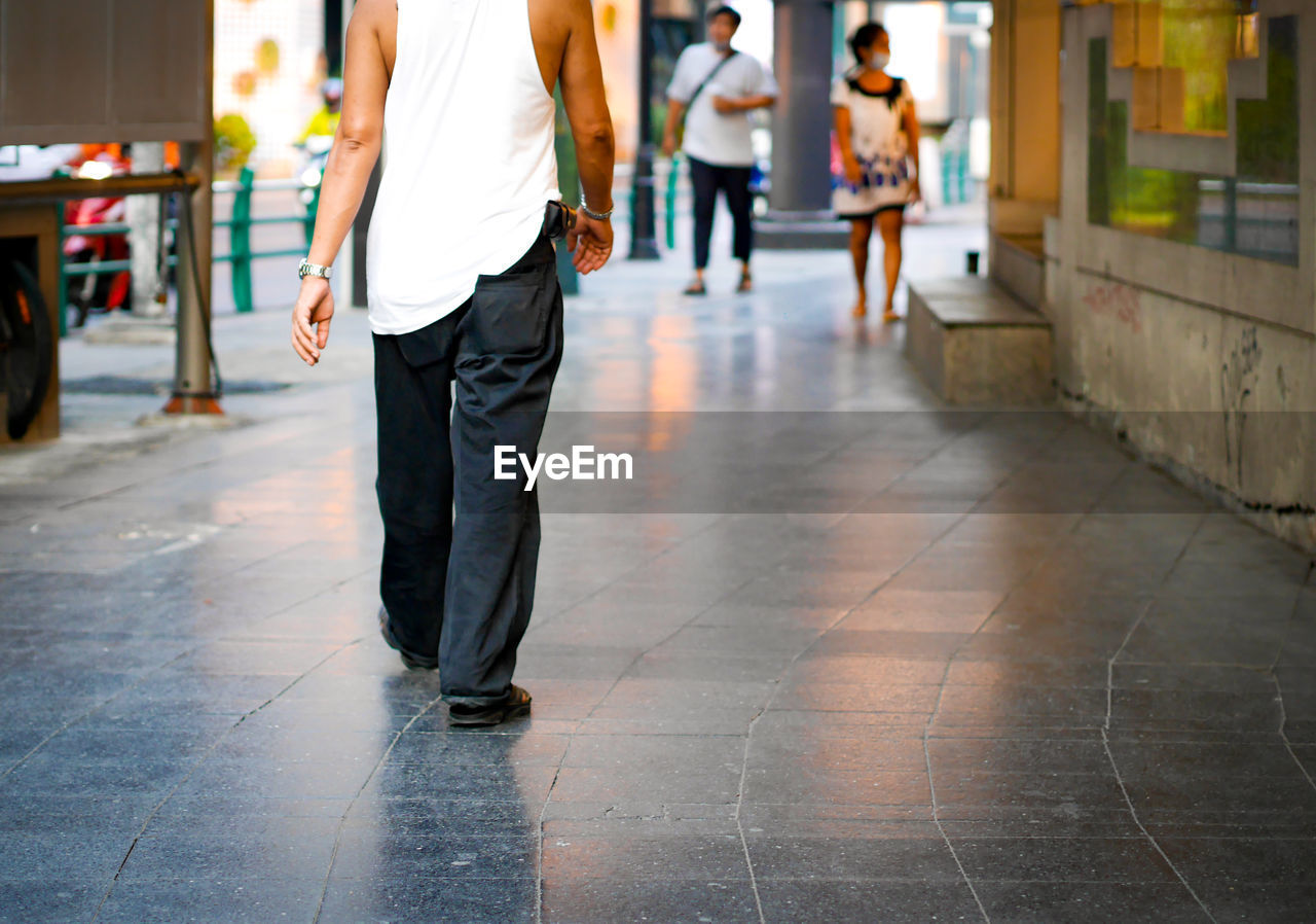 Low section of men walking on sidewalk in city