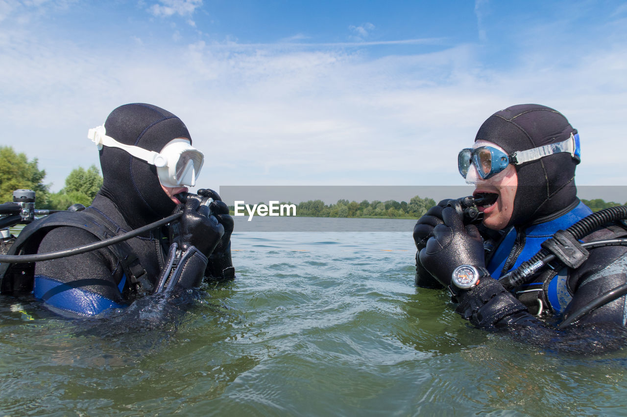 Young man and woman with diving suit in sea