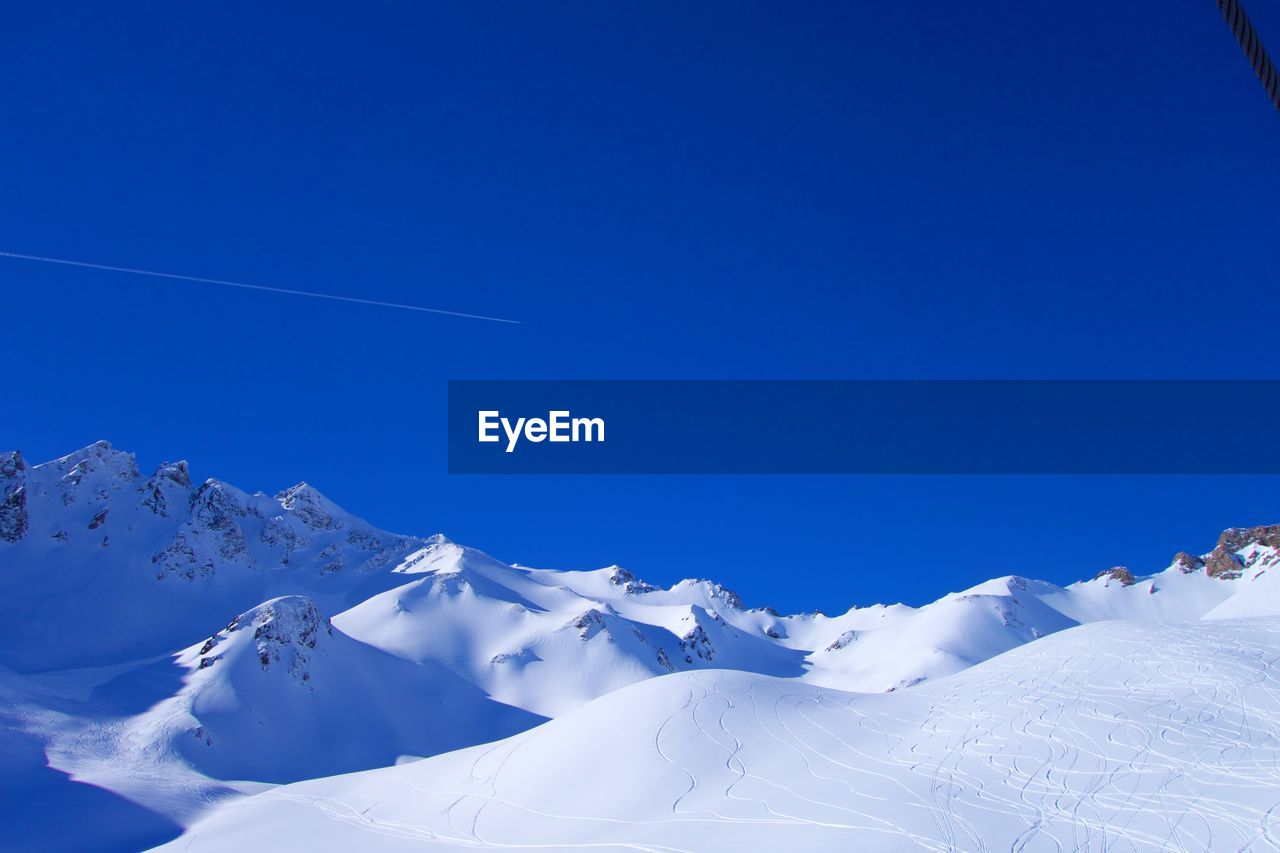 Scenic view of snowcapped mountains against clear blue sky