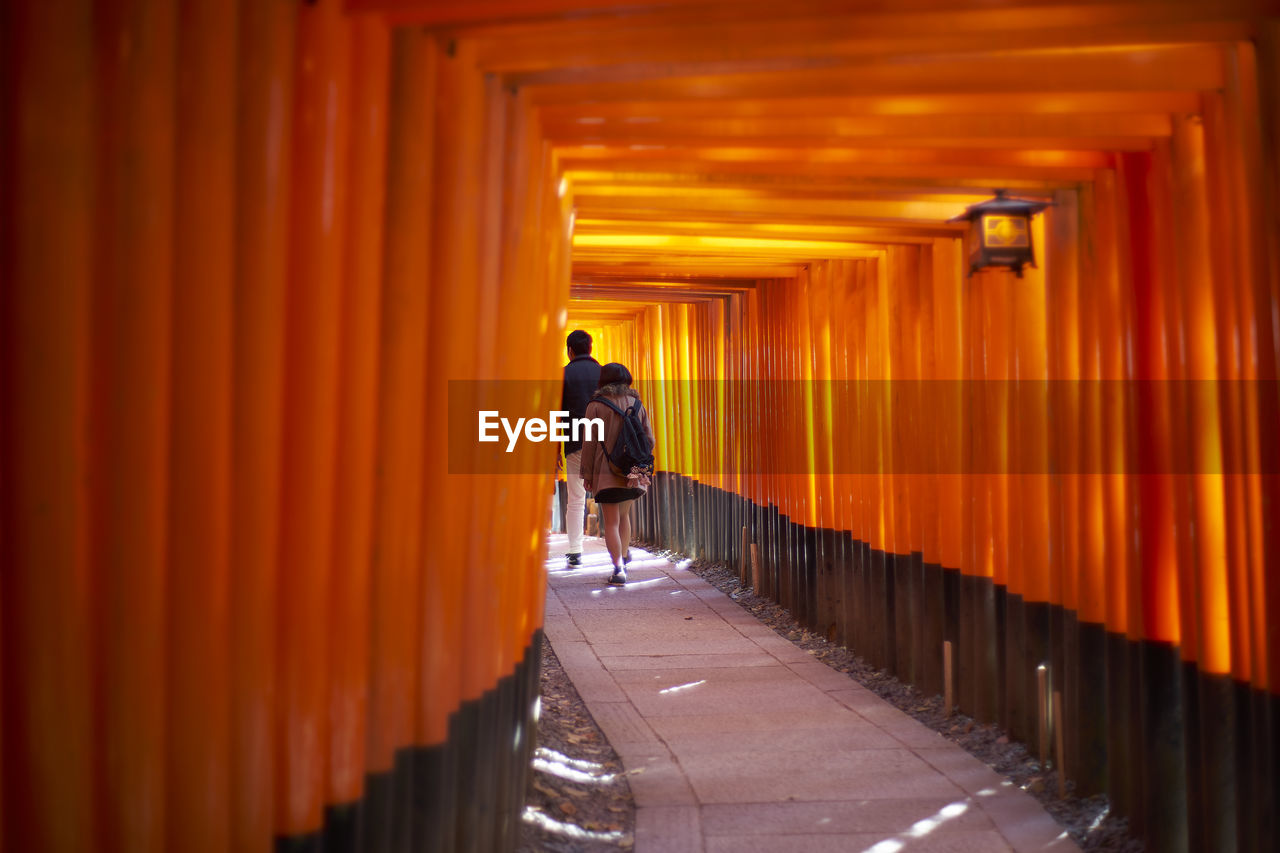 Rear view of people walking in torii gate