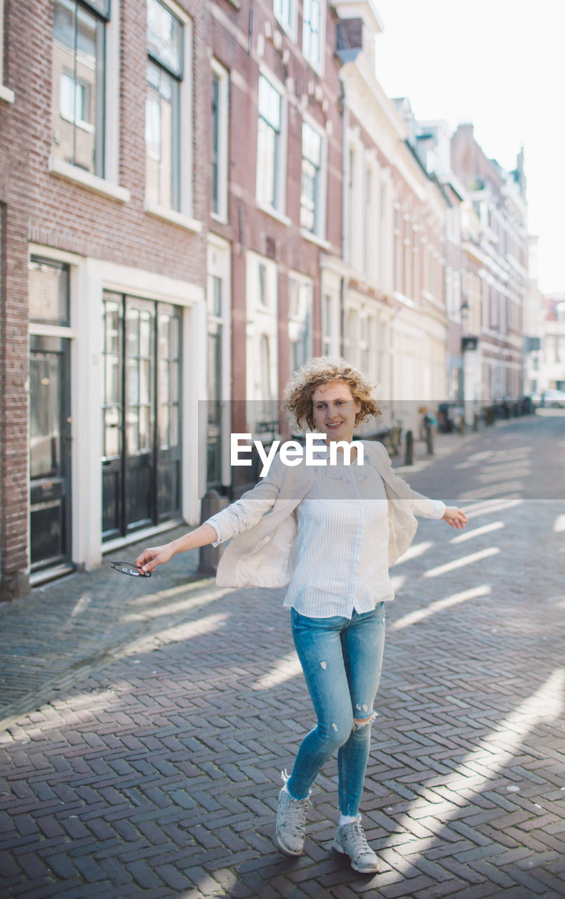 Smiling woman standing on street by buildings