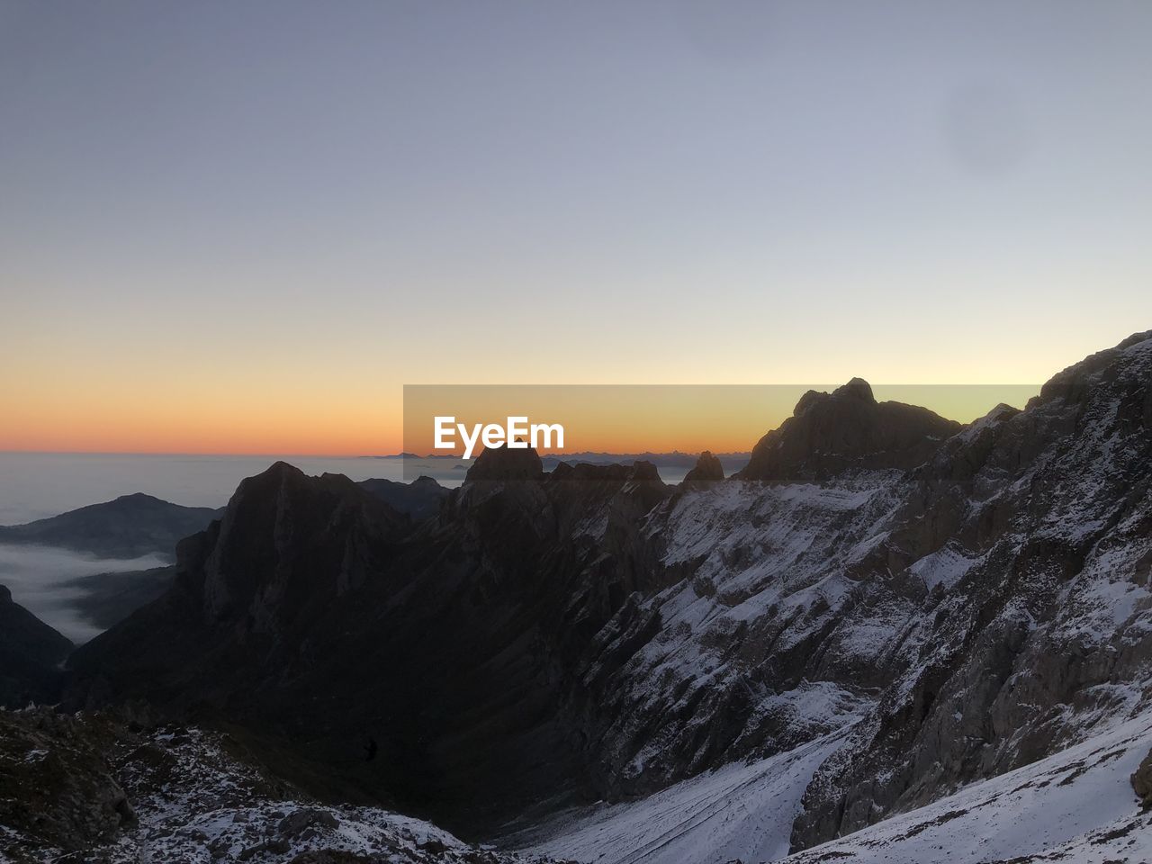 Scenic view of snowcapped mountains against clear sky during sunset