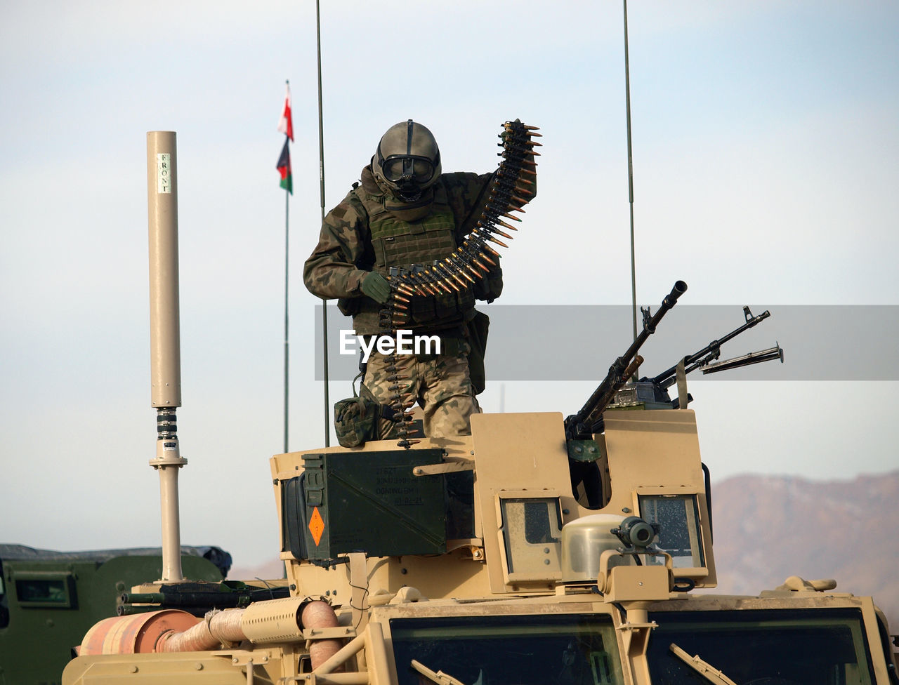 Army soldier holding bullets while standing in armored tank