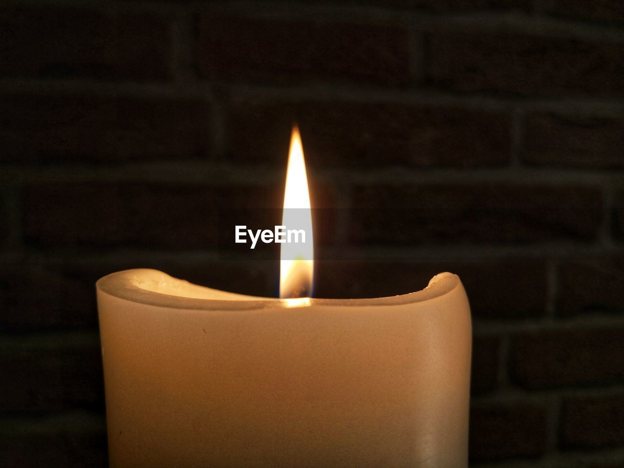 CLOSE-UP OF LIT CANDLE IN THE DARK