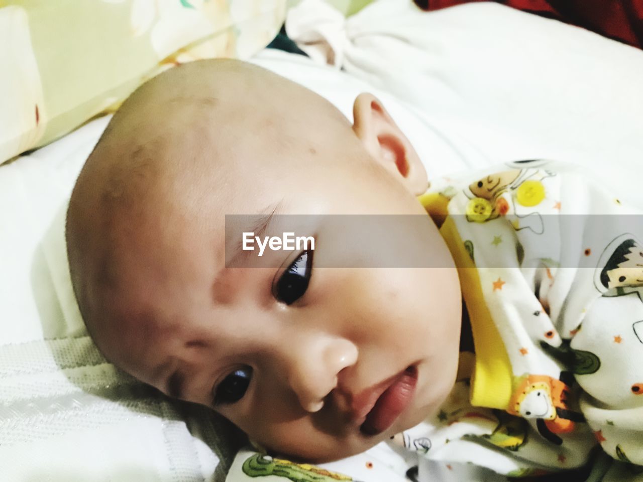 CLOSE-UP PORTRAIT OF CUTE BABY LYING ON SOFA