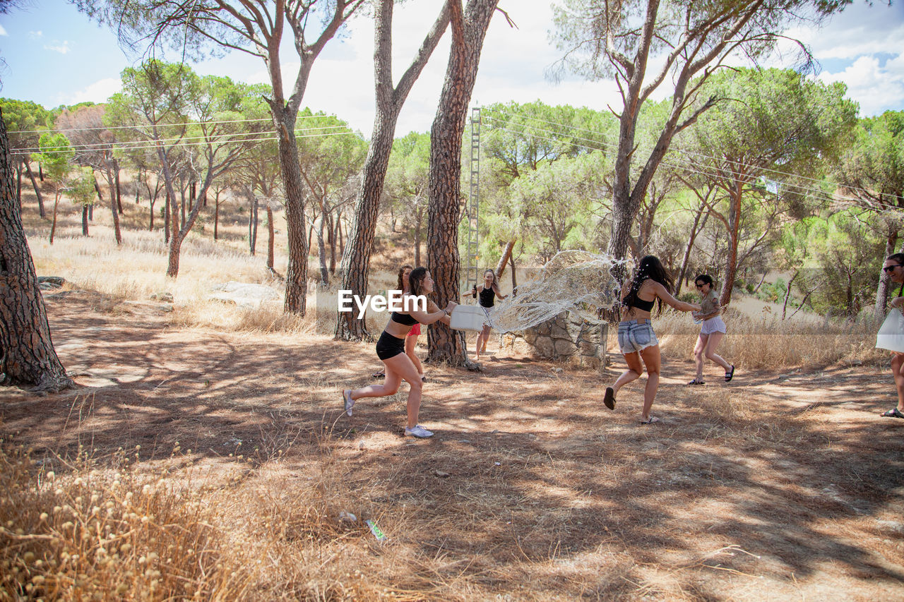 Female friends playing with water in forest