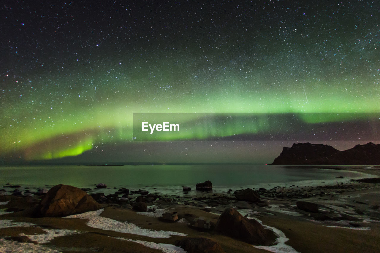 Scenic view of sea against aurora borealis at night