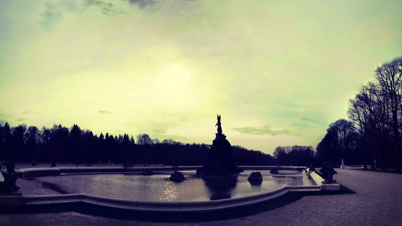 Artificial pond in park against cloudy sky