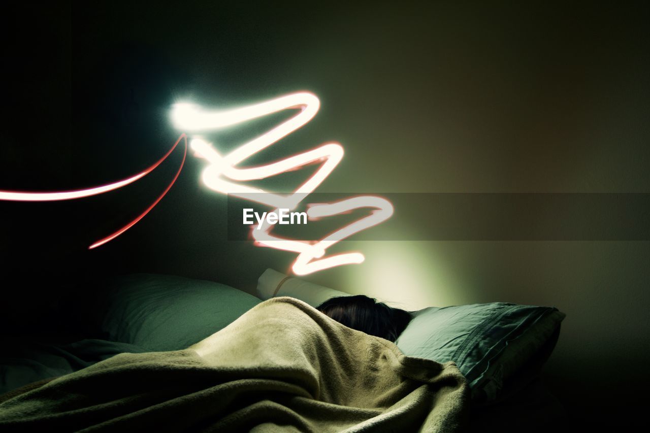 Light painting over woman sleeping on bed