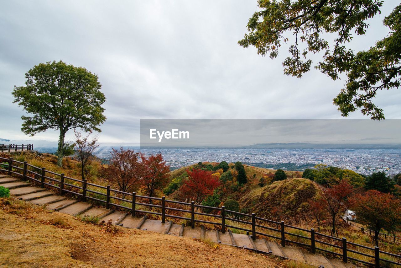 High angle view of footpath by trees against cloudy sky during autumn