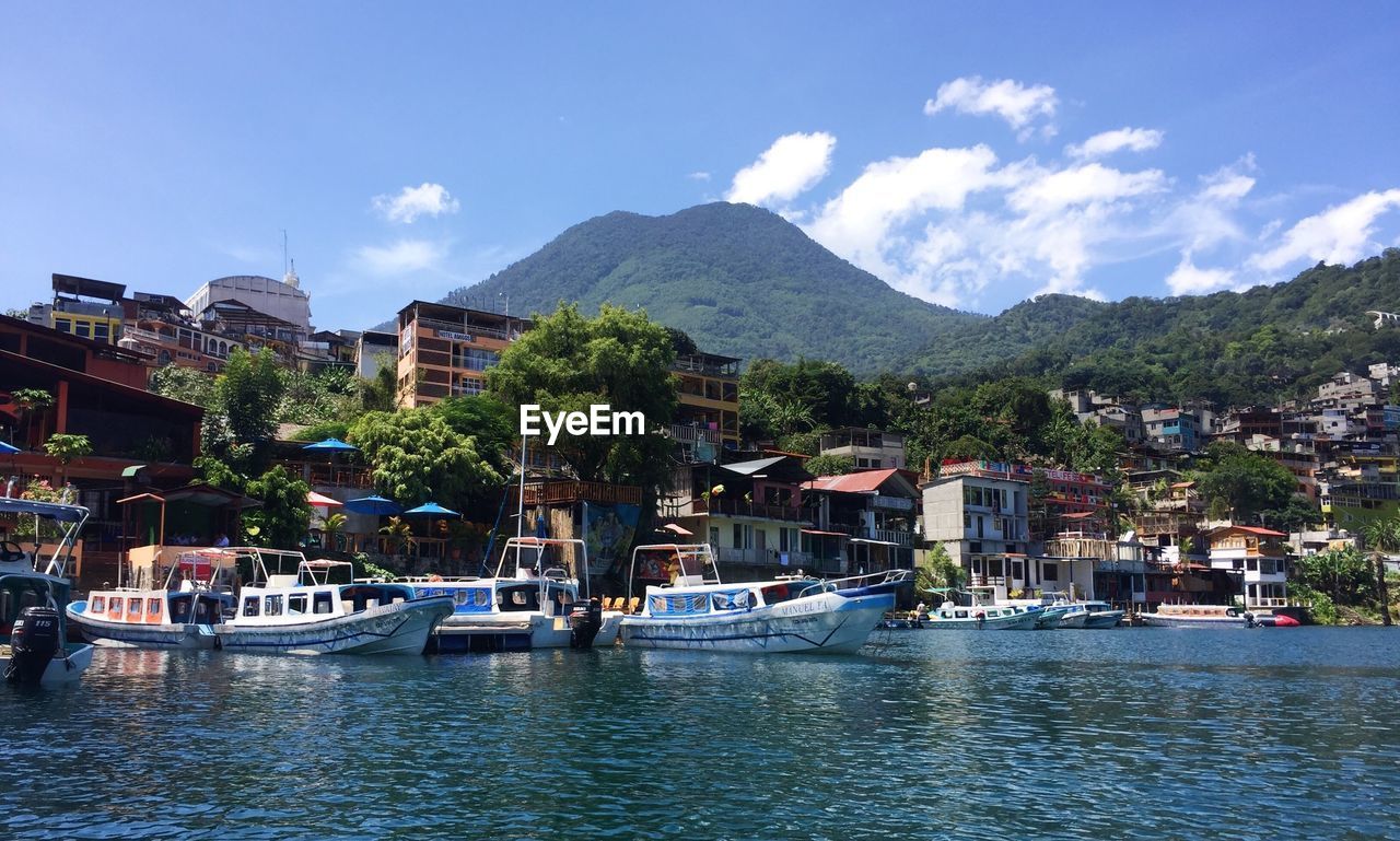 Sailboats in city by buildings against sky