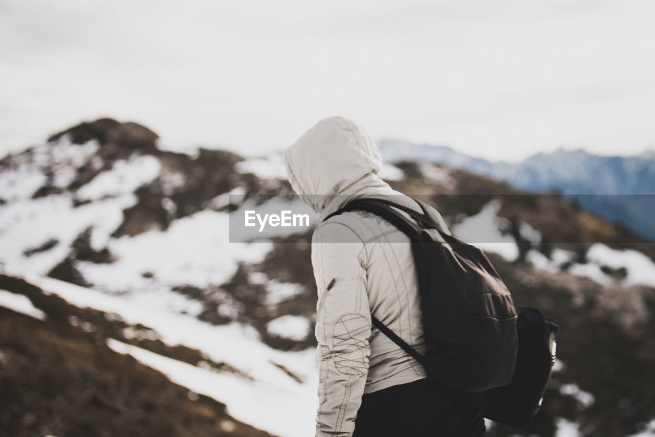 Side view of backpacker wearing hooded jacket on mountain