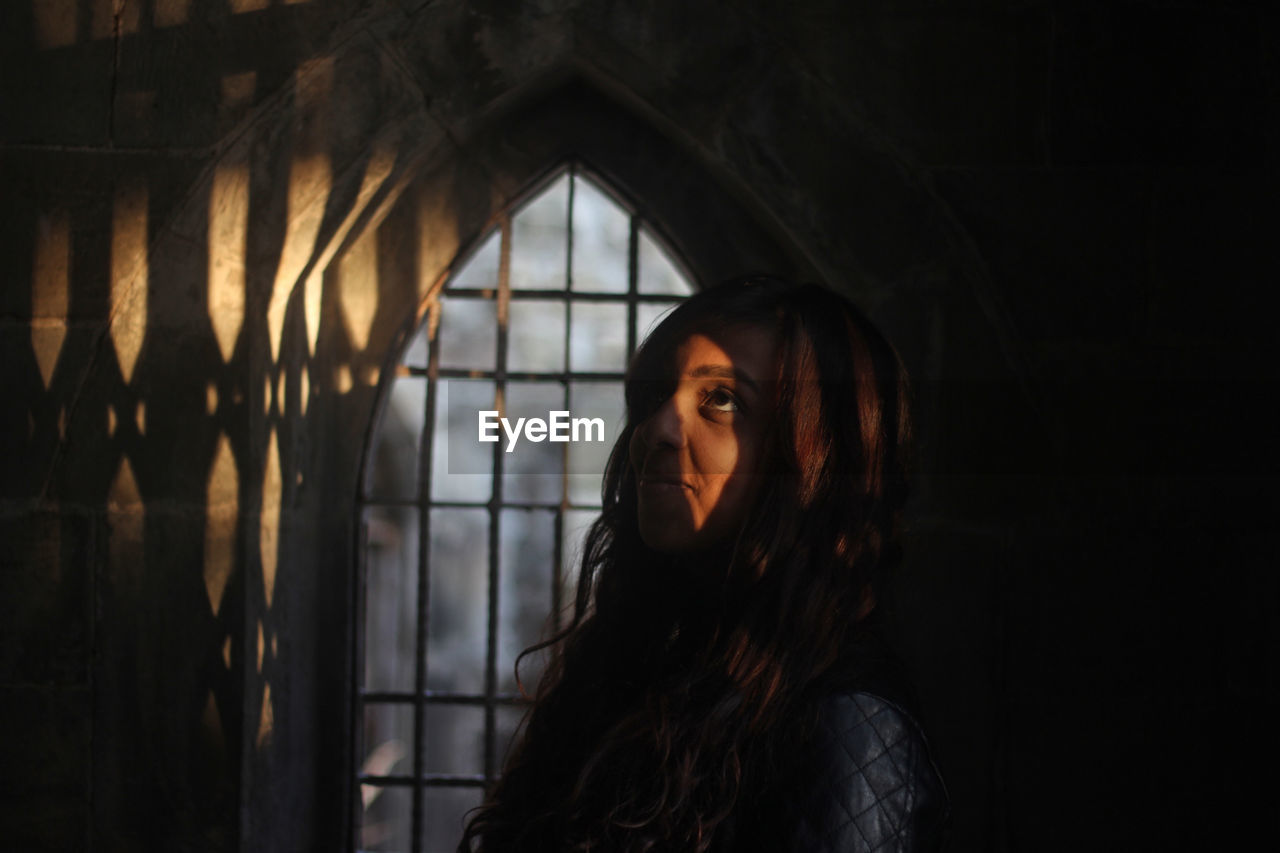 Woman looking up standing against window