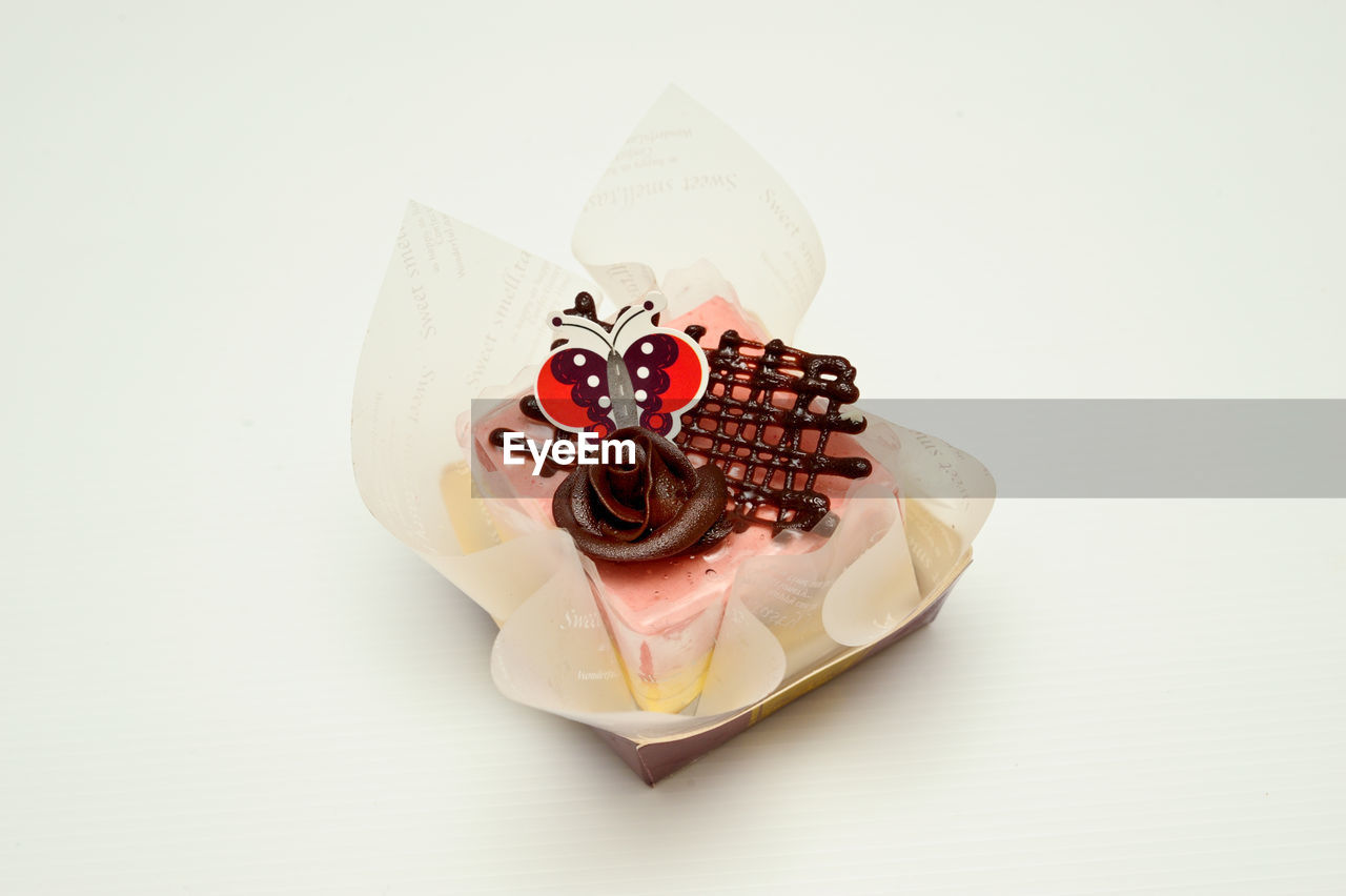 Delicious colorful creamy cheesy sponge chocolate fruit cake against white background
