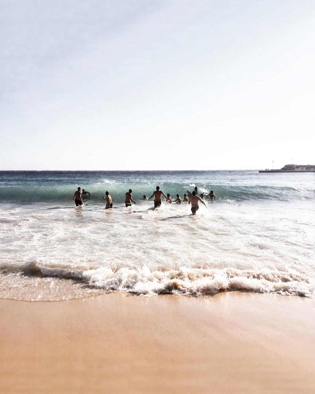 PEOPLE ENJOYING AT BEACH AGAINST CLEAR SKY