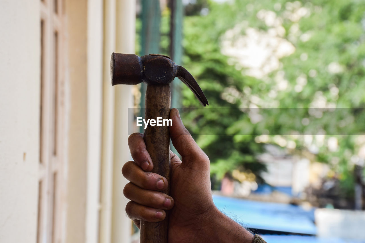 CLOSE-UP OF HAND HOLDING METAL OUTDOORS