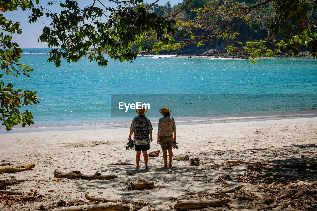 Rear view of couple standing at beach