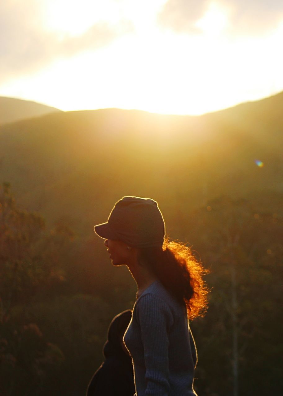 Woman standing against mountain during sunset