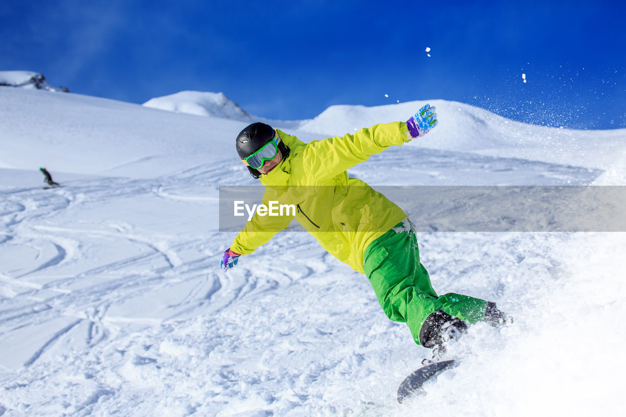 Low angle view of young man skiing on snowcapped mountains during winter